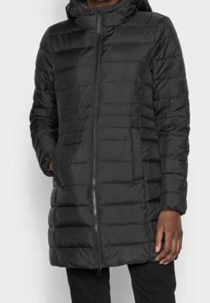 Osoba nosząca czarną pikowaną, puchową kurtkę z kapturem, zapinaną na zamek z przodu, z bocznymi kieszeniami, stojąca na jednolitym tle.