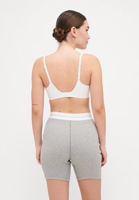 Hvit bralette med justerbare stropper, med en lav ryggdesign, kombinert med grå teksturerte shorts med en hvit elastisk midje.