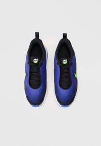 Par plavih i crnih Nike Air Max tenisica s zelenim logotipima, crnim vezicama i bijelim potplatima, prikazanih odozgo na bijeloj pozadini.