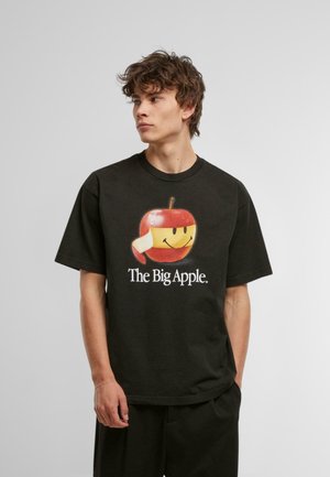 Svart t-skjorte laget av bomull med et fargerikt eple-graphic med et smil og teksten "The Big Apple" i hvitt under. Korte ermer.