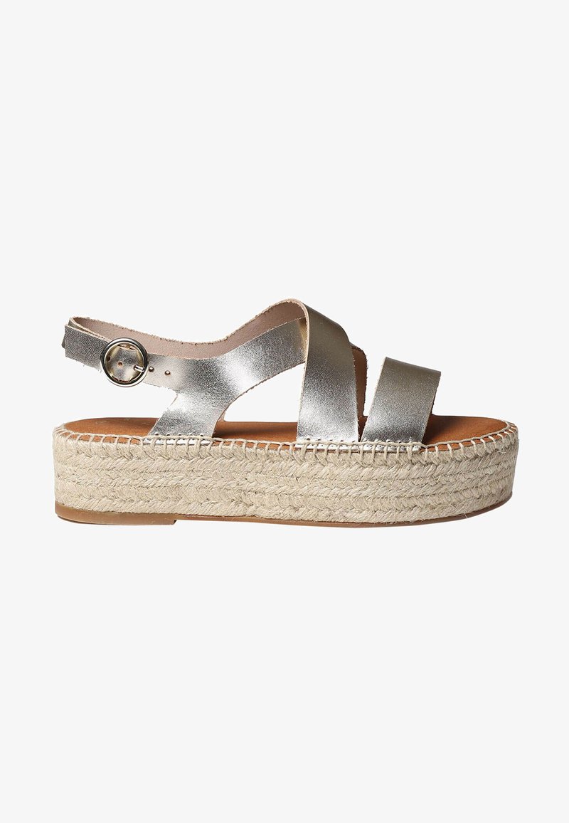 Metallic silver espadrille sandals with crisscross straps, adjustable ankle buckle, and woven jute platform sole. Smooth leather texture.