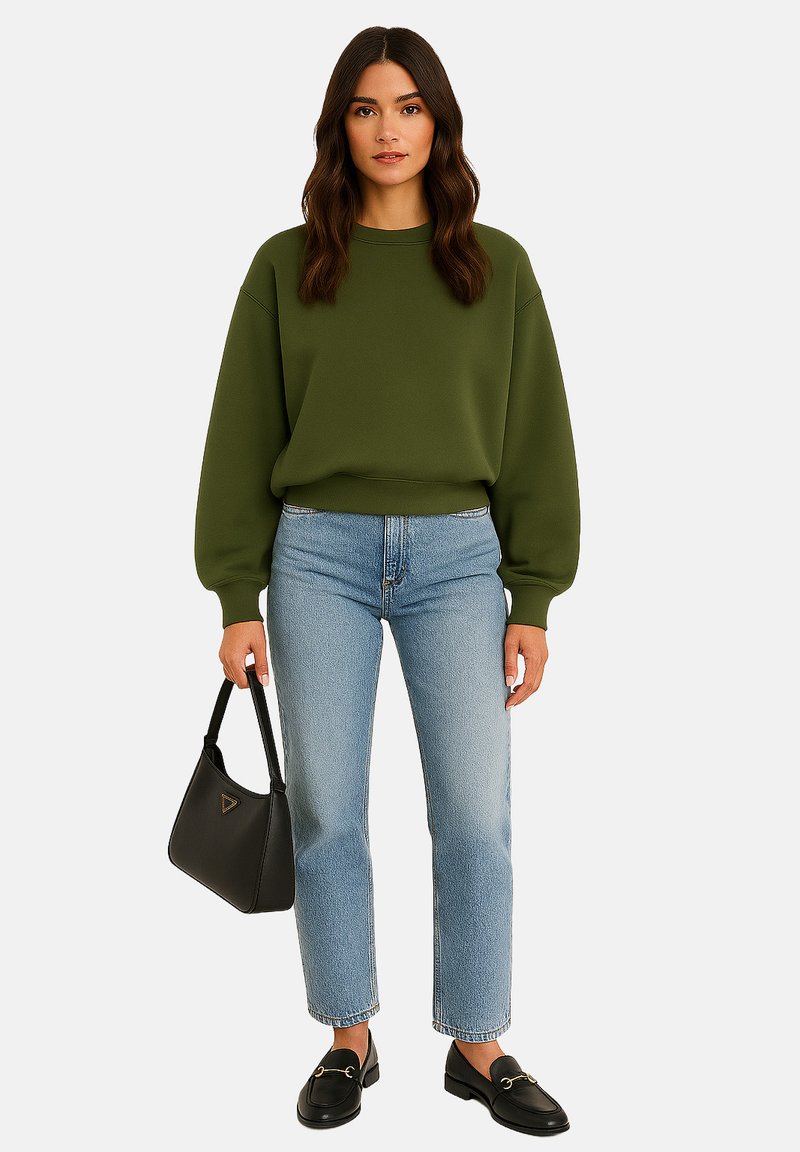 Olijfgroene sweatshirt met dropped shoulders, gecombineerd met lichtblauwe straight-leg jeans. Een zwarte handtas en loafers maken de look compleet.