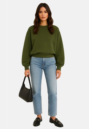 Olijfgroen fleece sweatshirt met verlaagde schouders, lichtblauwe recht gesneden jeans, zwarte loafers en een zwarte schoudertas met een logo.