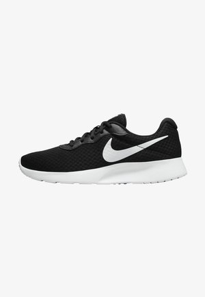 Czarne buty sportowe z siateczkową cholewką, z białym logo Nike w kształcie „swoosh”, okrągłym czubkiem i białą podeszwą. Sznurowany design z wyściełanym kołnierzem.