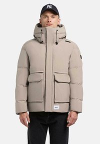 Light beige puffer jacket with a high collar, drawstring hood, and front flap pockets. Features black accents and a brand label at the hem.