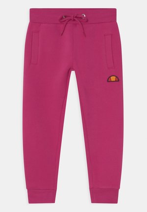 Pantalon de jogging rose fuchsia avec taille en côte, lien de serrage, poches latérales, poignets côtelés et un petit logo orange et noir sur la cuisse gauche.