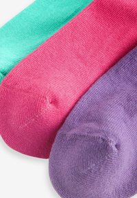 Drei Paar Socken: eine in Teal, eine in Pink und eine in Lila. Jede Socke hat eine glatte Strickstruktur und ein rundes Zehendesign.