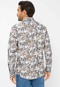 Camicia a maniche lunghe con un motivo floreale multicolore in tonalità di blu, marrone e bianco. Colletto con bottoni e orlo curvo.