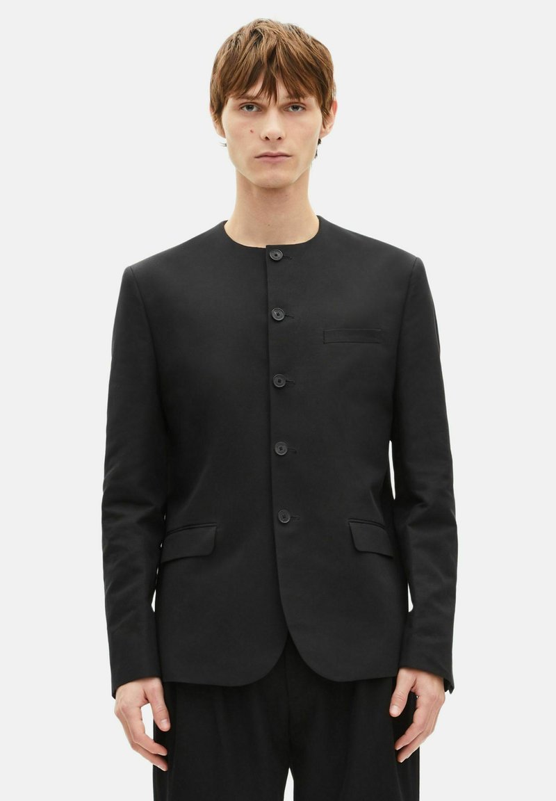 Black blazer made of smooth fabric featuring a round neckline, front button closure, two side pockets, and a single chest pocket.