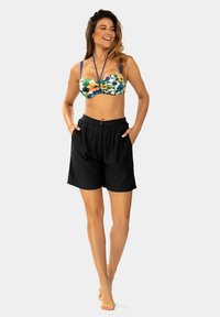 Kolorowy kwiatowy top bandeau z cienkimi ramiączkami w zestawieniu z czarnymi szortami o średnim stanie, z zapięciem na guzik i kieszeniami po bokach.
