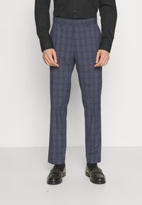 Navy plaid trousers featuring a tailored fit, side pockets, and a smooth fabric texture. Worn with a black button-up shirt and black shoes.