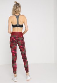 Leggings deportivos en un patrón de camuflaje rojo, marrón y rosa. Tejido suave con una cintura alta y un diseño ajustado y ceñido. Sujetador deportivo de contraste.