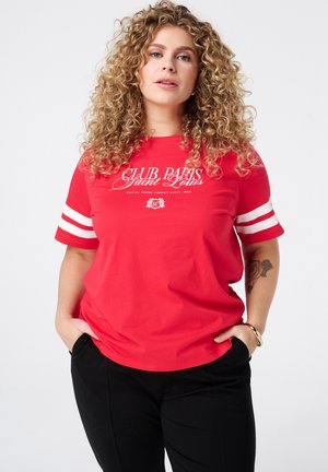 T-shirt en coton rouge à manches courtes, avec des rayures blanches sur les manches, et un imprimé graphique centré sur la poitrine avec les mots "CLUB PARIS Saint Louis".