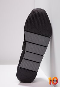 Svart sneaker sula med en texturerad yta. Har framträdande Calvin Klein Jeans-logotyp och ett geometriskt mönster.