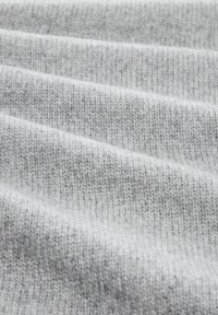 Țesătură tricotată de culoare gri deschis, cu un model de nervuri vizibile, având o textură moale și nuanțe ușor variate, care creează o adâncime subtilă.