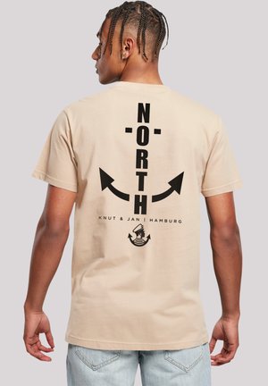 Beige cotton t-shirt featuring a large black graphic design on the back, reading "NORTH" with arrows and text below. Standard fit.