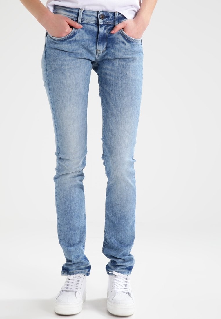 Světlé modré džíny skinny s vybledlým povrchem, dvěma předními kapsami a klasickým zipem. V kombinaci s bílými teniskami.