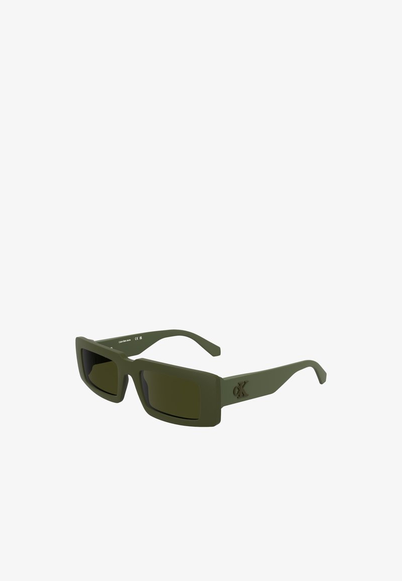 Gafas de sol mate verdes con forma rectangular, lentes oscuros y detalle de logo en relieve en el lateral. Montura de plástico ligera.