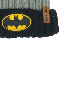 Berretto lavorato a maglia con parte superiore grigia e risvolto nero. Presenta un patch del logo di Batman giallo e nero e un'etichetta in pelle marrone.