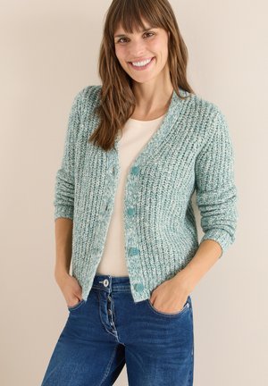 Lys teal strik cardigan med et struktureret mønster, udstyret med seks runde knapper og ribbede manchetter. Sammen med en cremet top og blå jeans.