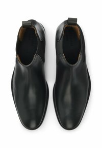 Czarne skórzane botki za kostkę z elastycznymi wstawkami po bokach, zaokrąglonym czubkiem i pętelką z tyłu. Gładka faktura i wąska podeszwa.