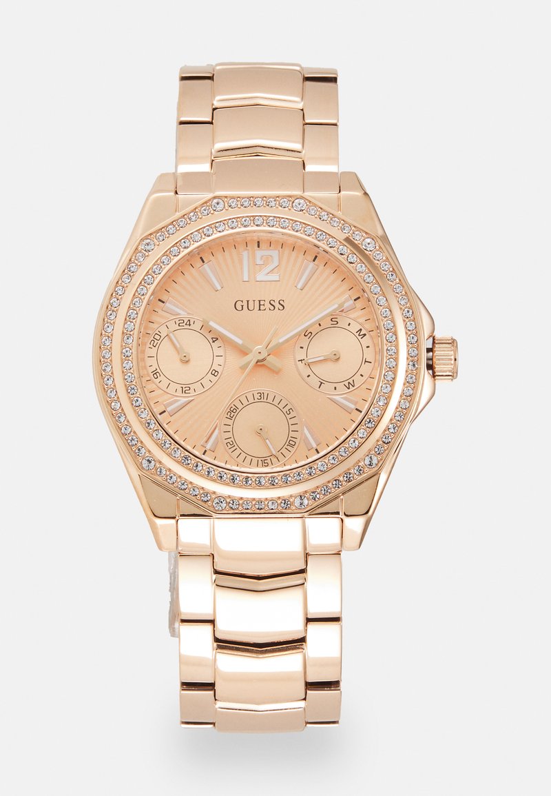 Relógio em metal dourado com uma caixa redonda, bezel decorado com cristais, mostrador rosa dourado, três submostradores e uma pulseira de elos.