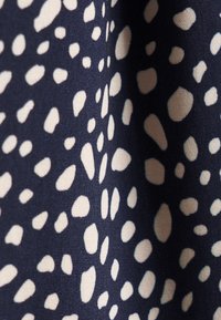 Tessuto blu navy con forme organiche color crema sparse, che creano un motivo testurizzato. Il materiale appare liscio con una leggera lucentezza.