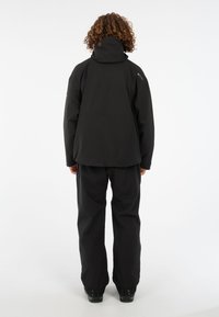 Juodas vandeniui atsparus švarkas su aukštu apykakle, laisvo kirpimo ir reguliuojama kapišonu. Derinamas su suderintais juodais kelnėmis ir batais.