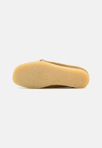 Leather shoe sole with a textured yellow rubber bottom, featuring a rounded shape and minimal depth, designed for comfort and durability.
