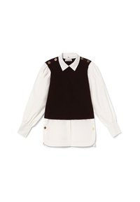Schwarzes ärmelloses Oberteil mit goldenen Knopfakzenten, über einem weißen Langarmshirt mit spitzem Kragen und plissierten Ärmeln geschichtet.