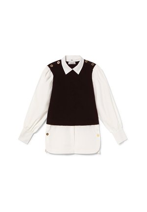 Zwarte mouwloze top met gouden knoopaccenten, gelaagd over een witte blouse met lange mouwen, featuring een puntige kraag en geplooide mouwen.