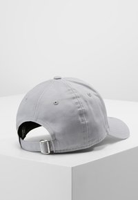 Szürke, ívelt karimájú baseball sapka, pamutból készült. Hátsó pánttal rendelkezik, fém csattal és varrott részletekkel. Nincs látható logó.