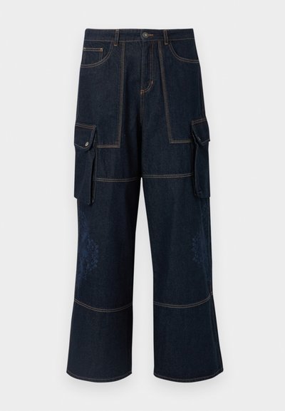 Jean cargo en denim foncé, avec poches à rabat, coutures contrastées, jambes larges et un motif floral subtil sur le bas.