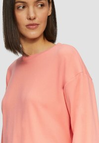 Roze sweatshirt met een ronde hals, lange mouwen en een zachte, textuurstof. Het ontwerp met drop shoulder zorgt voor een comfortabele pasvorm.