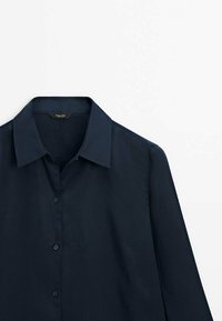 Chemise bleu marine à boutons en tissu lisse, dotée d'un col classique et de manches longues avec des détails de boutons.