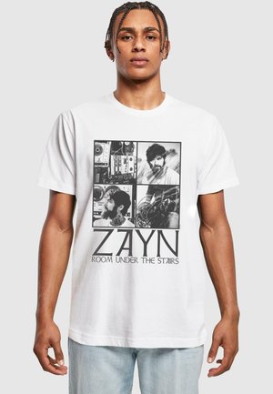 Hvid bomulds t-shirt med et sort-hvidt grafik, der har fire fotopaneler og teksten "ZAYN ROOM UNDER THE STAIRS" i fede bogstaver.