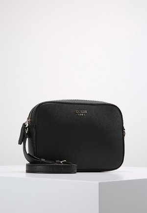 Sac bandoulière noir Guess avec surface texturée, fermeture éclair argentée, sangle réglable et logo "Guess 1981" à l'avant.