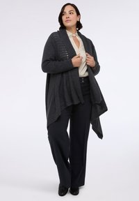 Tmavě šedý cardigan s otevřeným předním dílem, s ribbed texturou, jemnými vzorci a splývavým lemem, v kombinaci s námořnickými kalhotami.