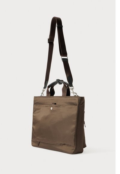 Ruda audinio pasiuntinių krepšys su reguliuojamu diržu, viršutinėmis rankenomis, priekiu kišene ir sidabro spalvos apdailos detalėmis. Sklandus paviršius, stačiakampio formos.