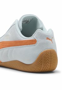 Pantof sport Puma cu un upper din suede bleu deschis, un accent din țesătură portocalie și o talpă din cauciuc maro, cu un model de profil texturat.