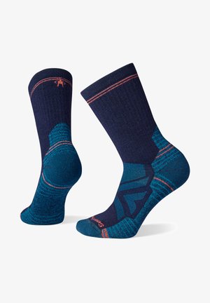 Meias azul-marinho com padrões geométricos em tom teal, com detalhes em rosa contrastante na bainha, e material texturizado para maior conforto.
