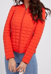 Giacca imbottita rossa con collo alto, zip frontale e due tasche laterali. Pannelli testurizzati su tutta la superficie e design aderente.