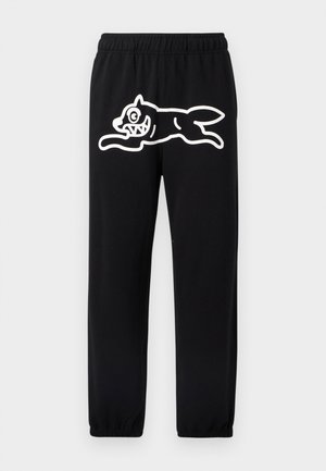 Svarte joggebukser med elastisk midjebånd, med en stor hvit tegneseriestil design av en hoppende skapning på venstre ben.