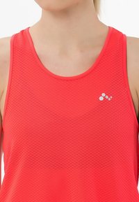 Camiseta atlética de malla roja con un cuello redondo y diseño sin mangas, con un pequeño logo blanco en el pecho.
