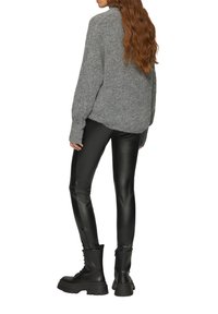 Grijze, oversized gebreide trui, zwarte nepleerleggingen en zwarte combatboots met stevige zolen. Gelaagd stof en slim-fit ontwerp.