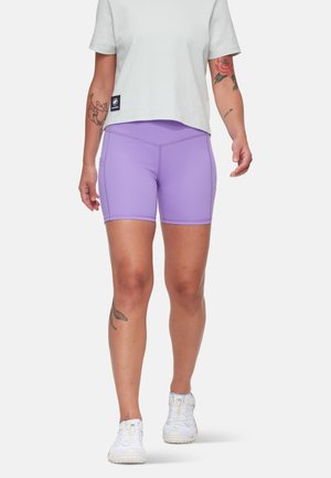 Lichtpaarse sportshorts van een gladde, rekbare stof met contrasterende stiksels, gecombineerd met een los lichtgrijs T-shirt en witte sneakers.