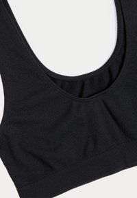 Sujetador deportivo negro con un escote amplio y redondeado, textura de canalé suave y banda elástica en la parte inferior. Tejido suave con detalles de costura mínimos.