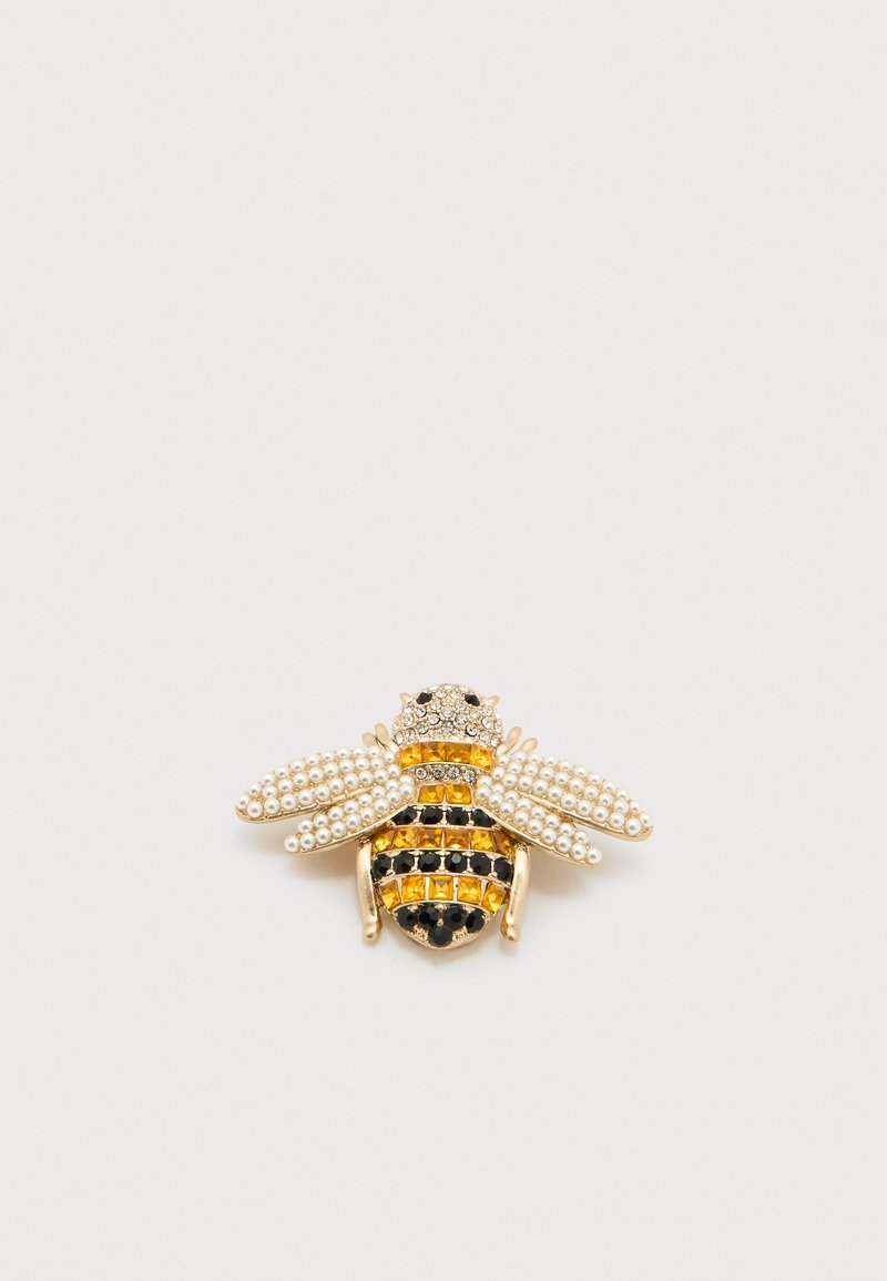 Καρφίτσα σε σχήμα μέλισσας με μεταλλικό χρώμα χρυσού, λευκά μαργαριτάρια, μαύρες και κίτρινες στρας, με λεπτομερή σχεδίαση φτερών και σώματος.