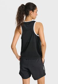 Black mesh athletic tank top with white trim, paired with black shorts featuring a logo. The fabric shows a breathable, lightweight texture.