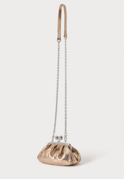 Petit sac pochette métallique couleur or rose avec une chaîne argentée et une fermeture à clip argentée, suspendu devant un fond uni.